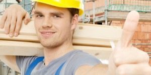 Bild eines Bauarbeiters, der einen gelben Schutzhelm mit seinem Daumen oben trägt